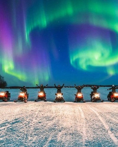 Snowmobile e aurora boreal no Ártico
